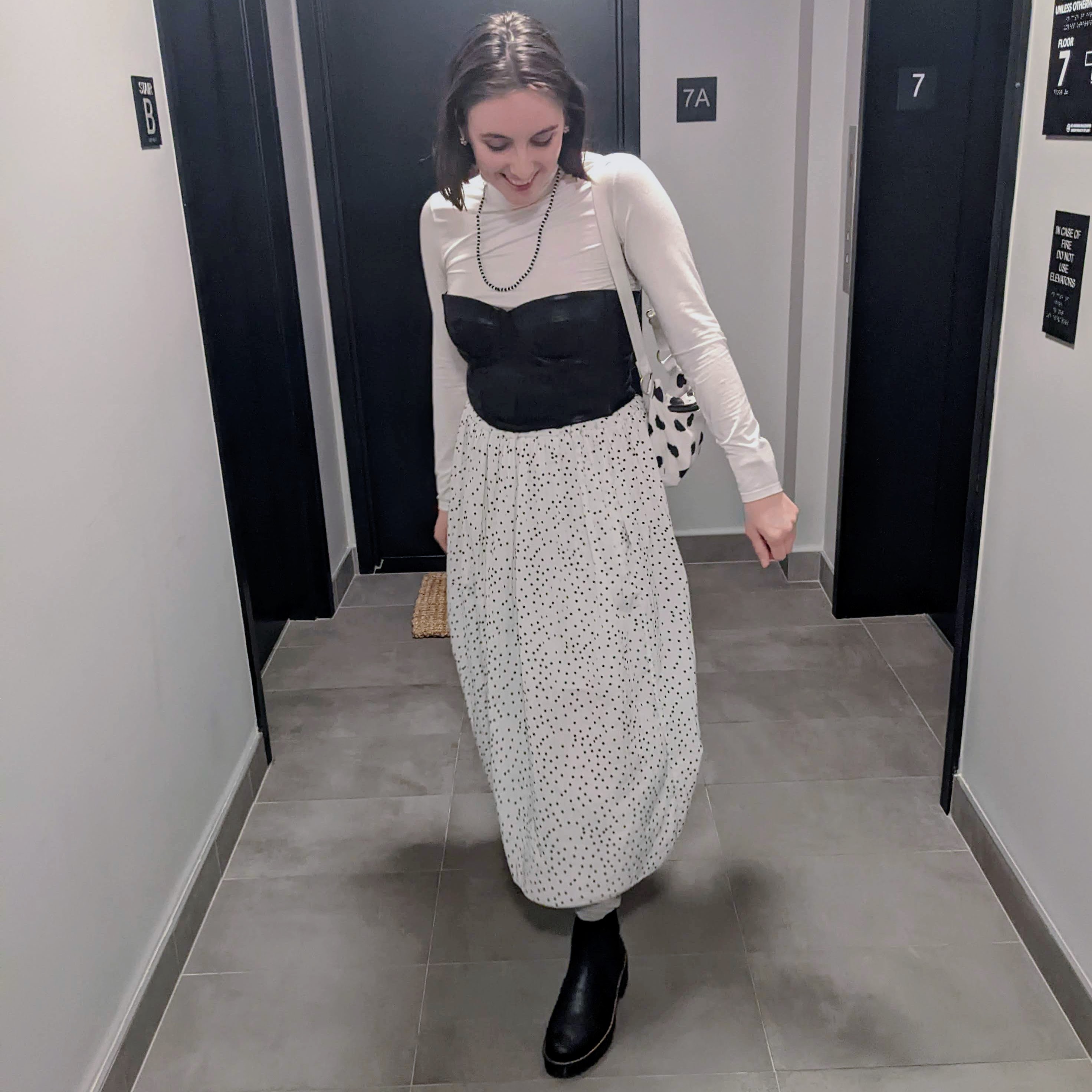Photo with white turtleneck under black leather bustier and white and black polka dot skirt